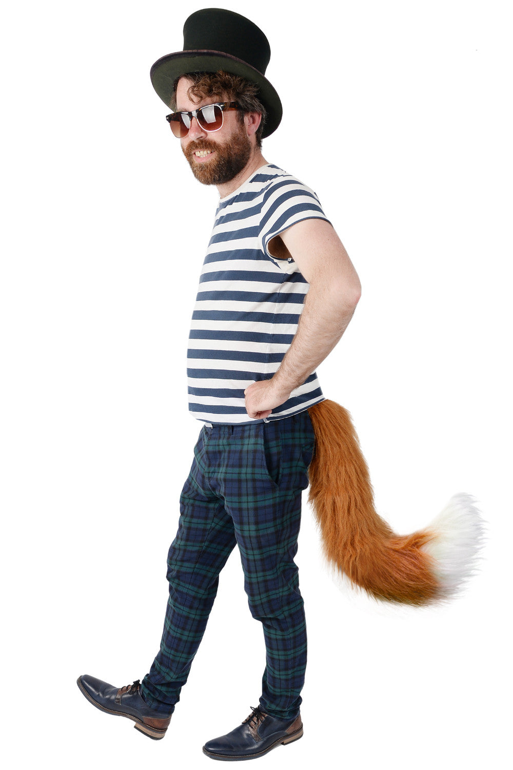 A bearded man in cosplay confidently struts in sunglasses, a top hat, a striped shirt, and plaid pants. His look is completed by The Fox, a large faux fox tail from TellTails swaying behind him, perfectly suited for the lively festival atmosphere.