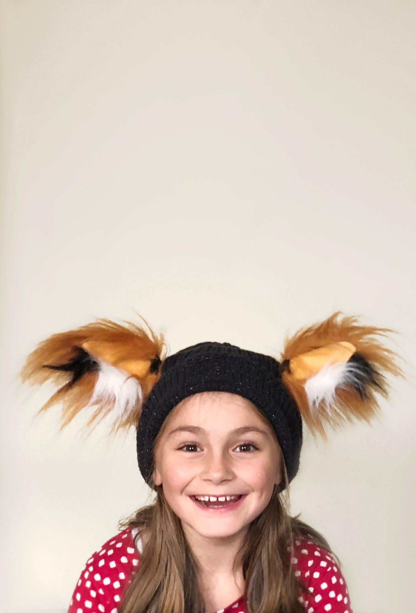 A girl aged 6 wearing TellTails fox animal ears attached with magnets to a black beanie, seems to have manifested a grin of extraordinary measure. Fancy dress novelty ears suitable for fox role play, cosplay, world book day characters. Animal woodland themed parties. Faux fur accessory, fantastic mr fox. Christmas present with matching tail. TellTails gift, stocking filler. Wearable animal ears. Halloween. As seen on dragons den by Deborah Meaden.