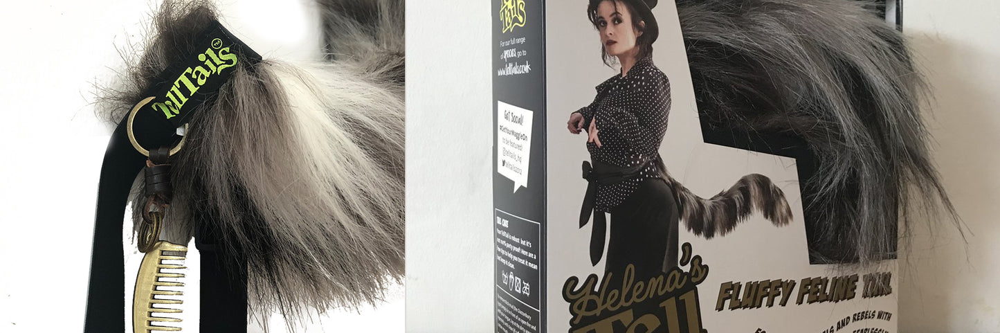 The Helenas Fluffy Feline Tail by TellTails, ideal for festivals or fancy dress, is shown on the box with a model wearing it. The text Fluffy Faux Fur accompanies the black and white tail, which is packaged securely with a zipper.