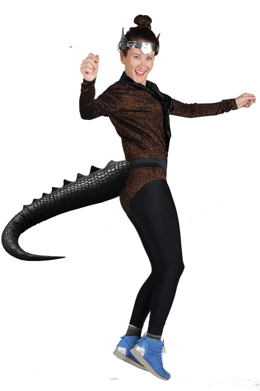 An adult or ‘big kid’ wearing a black dinosaur tail with a realistic scale pattern. It buckles on with a waistband that fits all. Perfect accessory for dino themed parties, jurassic world fans, kink parties, a day out with prehistoric friends at Natural History Museum, Character Toothless for World Book Week or Cosplay how to train your dragon. Fancy dress accessory for skiing and snowboarding on the slopes. Hen and stag party novelty accessories, twerk, Glastonbury, waggle to jungle at Boomtown. 