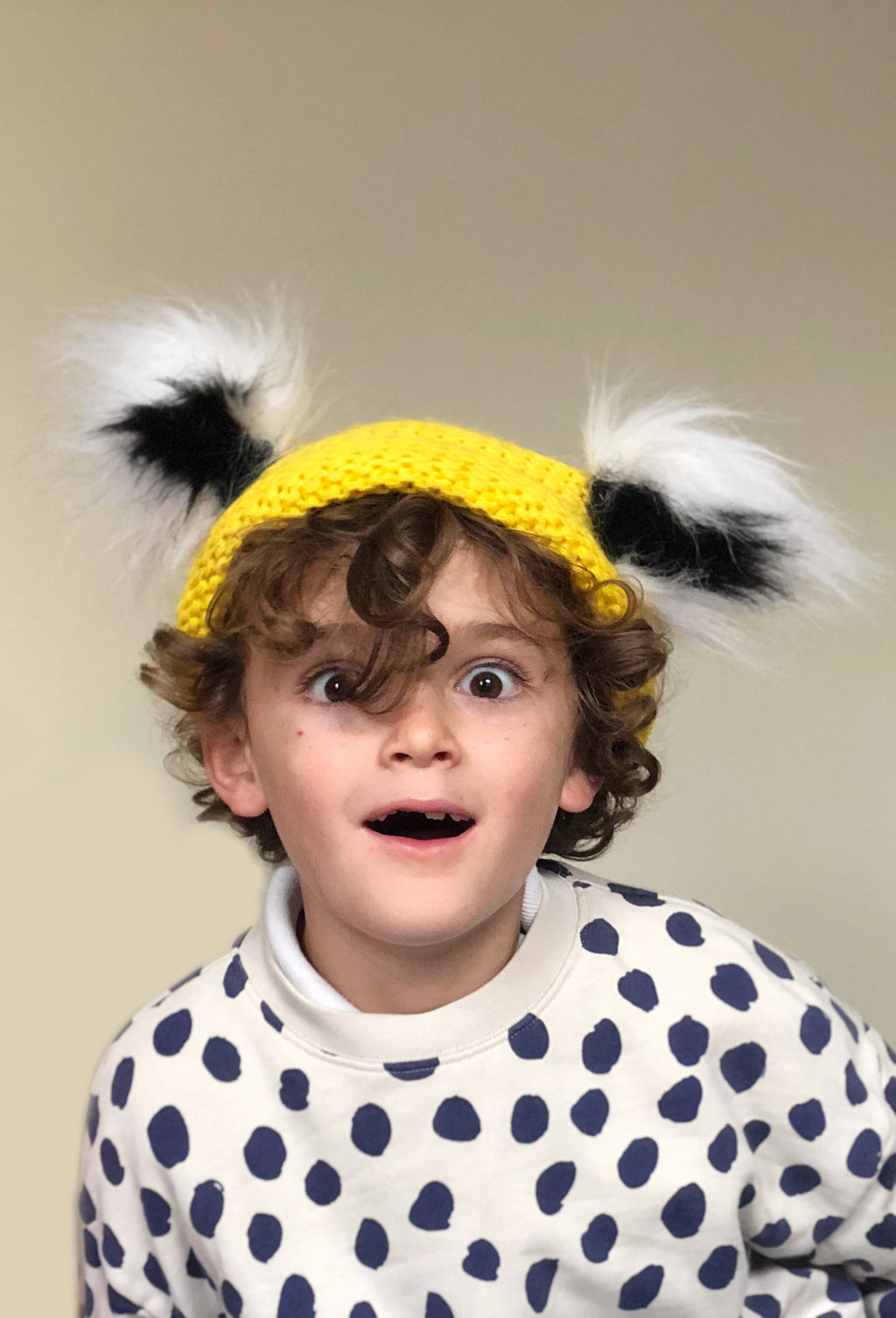 A toothless child aged 5 looks ADHD wearing Bobo Choses jumper and TellTails black & white animal ears attached with magnets to a yellow beanie. Fancy dress novelty ears suitable for lemur, cat, racoon role play, cosplay, world book day characters. Animal themed parties. Faux fur accessory, Character King Julien. Christmas present with matching tail. TellTails gift, stocking filler. Wearable animal ears. Beetlejuice, Dr Seuss for Halloween. As seen on dragons den by Deborah Meaden. 